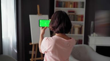 可爱的女孩谈话视频调用智能手机绿色屏幕站回来相机首页窗口背景画架帆布